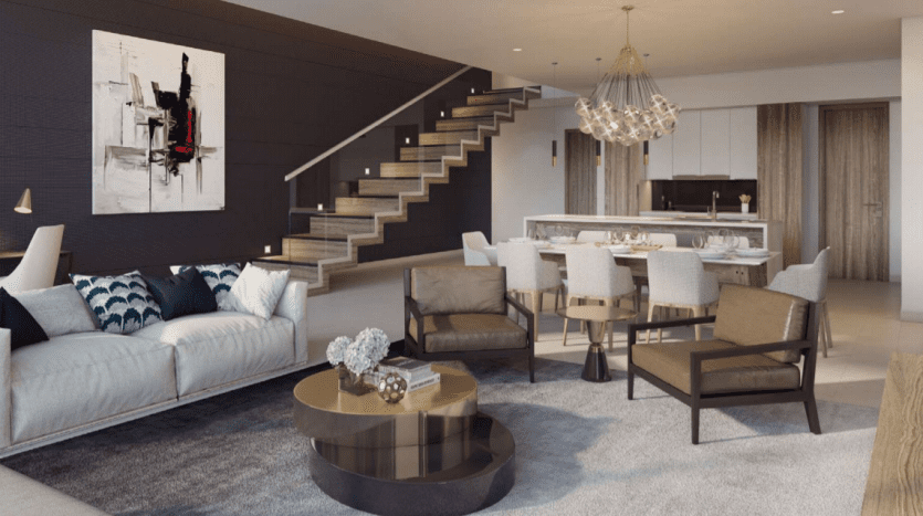 Salon moderne aux lignes épurées dans un appartement Dubaï, comprenant un canapé sectionnel, des fauteuils et une cuisine ouverte. Un escalier flottant mène à l’étage à côté d’une œuvre d’art murale abstraite.