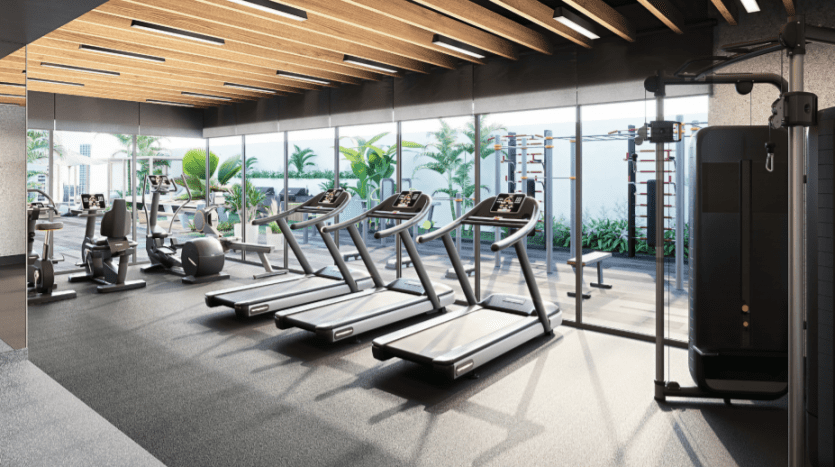 Intérieur de salle de sport moderne situé à Sloane JVC, comprenant une rangée de tapis roulants, de machines elliptiques et une station de musculation, bien éclairé par la lumière naturelle et un éclairage zénithal, avec un espace vert