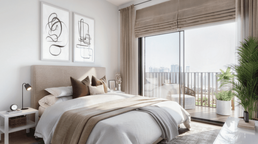 Une chambre moderne dotée d'un grand lit avec une literie beige et marron, des œuvres d'art abstraites au mur et de grandes fenêtres donnant sur Sloane JVC. Il y a un petit balcon visible à travers les portes coulissantes.