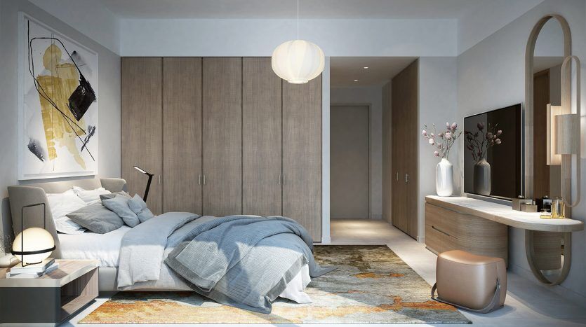 Intérieur de chambre moderne comprenant un lit gris moelleux avec des couvertures froissées, des meubles en bois élégants, un éclairage tamisé et des œuvres d'art murales abstraites dans la vallée de Dubaï, créant une ambiance chaleureuse et contemporaine.