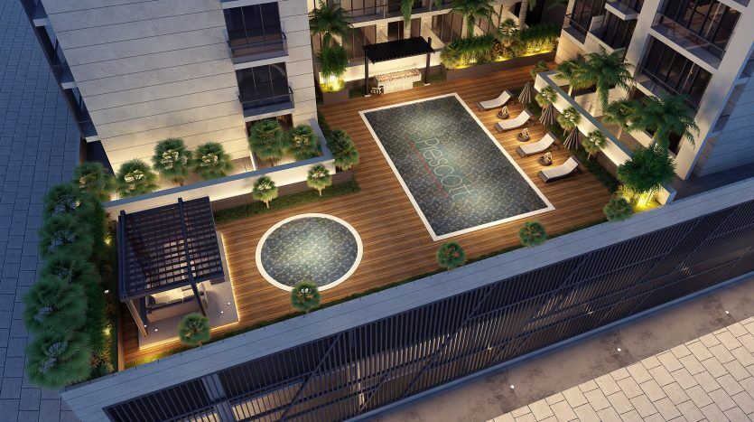 Vue aérienne d'une résidence premium de 3 salons sur le toit avec piscine, jacuzzi, transats et entourée d'une verdure luxuriante, subtilement éclairée au crépuscule.