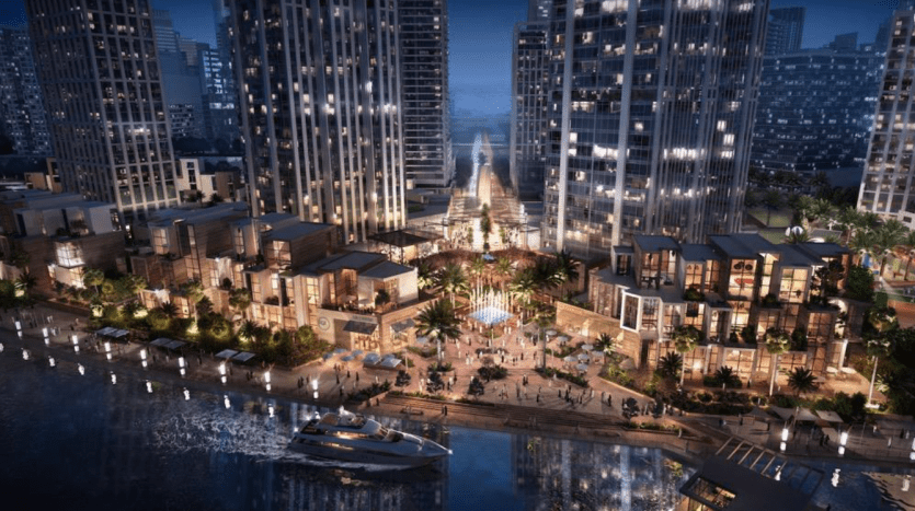 Une vue nocturne animée d'une promenade animée du front de mer du Peninsula Dubai, avec des immeubles modernes de grande hauteur, une place centrale éclairée avec une structure en forme de pyramide et des gens marchant tranquillement. Bateaux