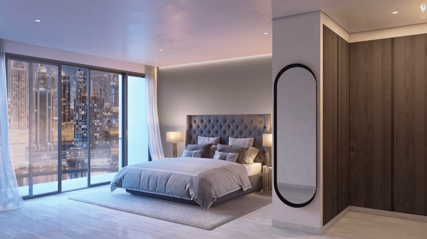 Chambre luxueuse avec un grand lit, un éclairage d'ambiance et des baies vitrées offrant une vue sur les toits de la ville la nuit. La chambre présente un design moderne avec des accents en bois et un tapis moelleux, gracieuseté de