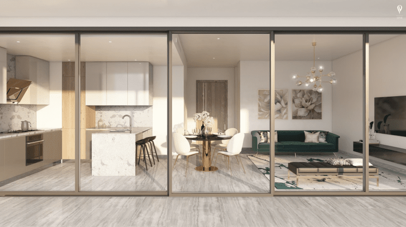 L'intérieur d'un appartement moderne, vu à travers de grandes fenêtres en verre, comprend une cuisine ouverte, un coin repas au décor élégant et un salon confortable avec un canapé vert, conçu par le groupe sélectionné à Dubaï.
