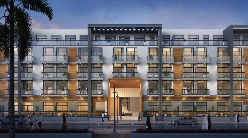 Façade d'un immeuble d'appartements moderne au crépuscule, présentant un design contemporain avec des balcons en verre et des lambris Panthéon Elysée 3. Les gens marchent et les voitures sont garées devant.