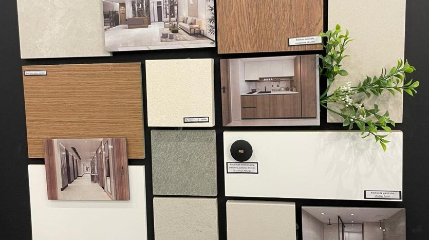 Un tableau d'affichage présentant divers échantillons de décoration intérieure pour l'immobilier Dubaï, notamment des textures de bois, de carrelage et de tissu, ainsi que des photographies d'intérieurs de pièces. Une petite plante décore un coin.