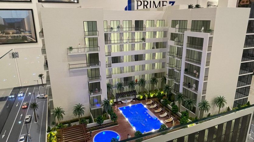 Maquette de Prime Residency 3, un complexe résidentiel moderne doté d'une piscine centrale, d'espaces paysagers et entouré de rues. Le bâtiment est exposé dans un décor intérieur avec éclairage.