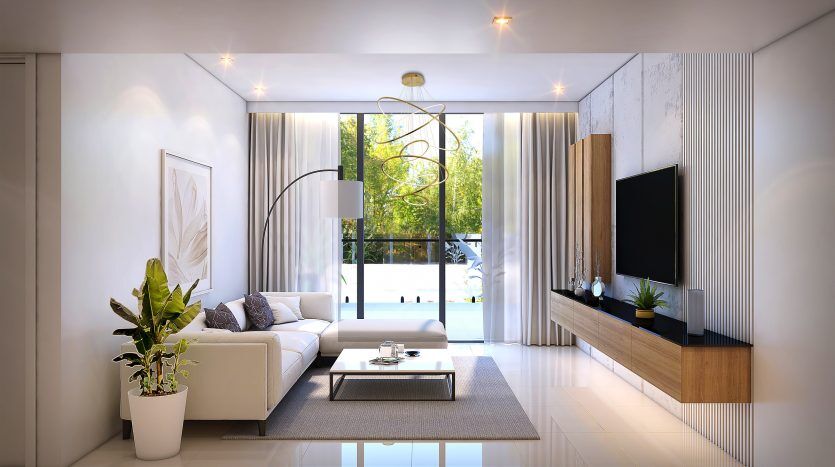Salon moderne du Prime Residency 3 avec des meubles blancs élégants, une grande télévision sur panneau en bois, de hautes fenêtres avec des rideaux transparents et des plantes d'intérieur. Lumineux et aéré avec un design minimaliste.