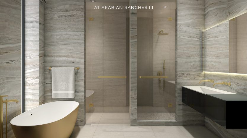 Intérieur de salle de bains luxueux avec murs et sols en marbre, une élégante baignoire ovale, une cabine de douche en verre et deux lavabos. Le design est accentué par des luminaires dorés et la marque subtile d'Elie Saab à