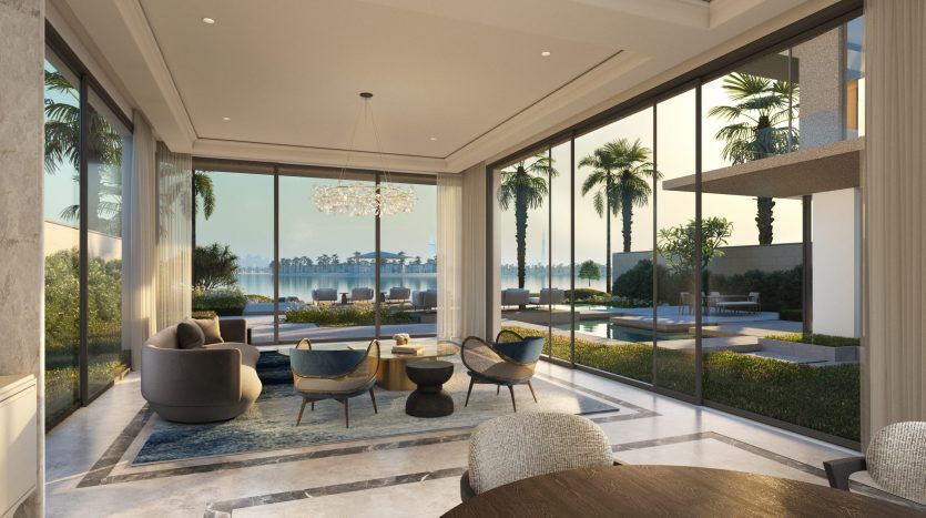 Salon luxueux avec de grandes baies vitrées offrant une vue panoramique sur un jardin tropical et le front de mer. La chambre dispose d'un mobilier élégant, d'un lustre élégant, d'une décoration inspirée des six sens et d'un sol en marbre.