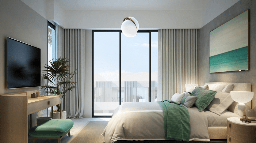 Une chambre moderne et bien éclairée comprenant un grand lit aux accents bleu sarcelle, des baies vitrées avec rideaux, une télévision à écran plat et une plante en pot offrant une vue sur un jardin extérieur.