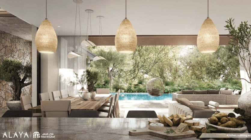 A modern, open-plan kitchen and dining room at Tilal Al Ghaf blends perfectly with an outdoor garden and pool, with natural materials and large glass windows offering views of the lush greenery and