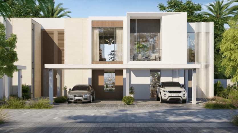 Résidence moderne de deux étages à Talia the Valley, présentant un design minimaliste avec une façade beige et blanche, de grandes fenêtres, un balcon et deux voitures garées sous une allée couverte, entourée de petits
