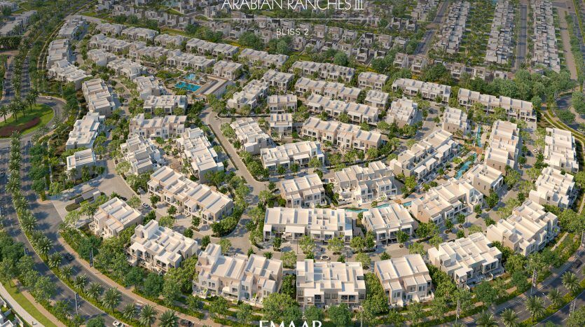 Vue aérienne d'Arabian Ranches III à Dubaï, présentant des rangées de villas modernes et uniformes avec une verdure luxuriante, des piscines communes et des rues organisées, le tout sous un soleil éclatant. Le logo "E