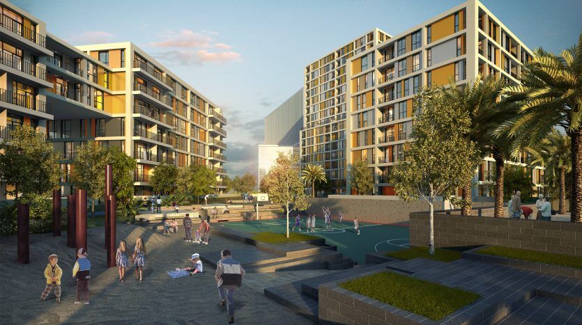 Une scène de parc communautaire dynamique avec des enfants qui jouent et des adultes qui socialisent, encadrée par des immeubles résidentiels modernes à plusieurs étages à Dubaï sous un ciel clair.