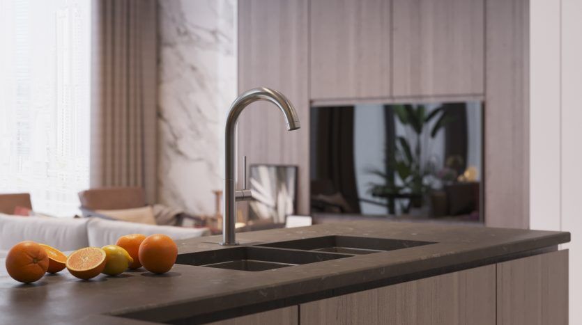 Un comptoir de cuisine moderne dans une villa de Dubaï, avec un robinet élégant, avec des oranges fraîches au premier plan et une vue floue d'un élégant espace de vie en arrière-plan.