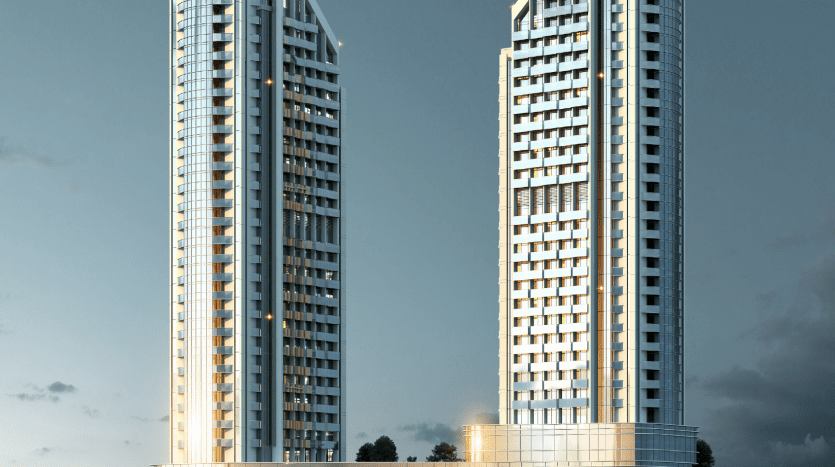 Deux grands gratte-ciel modernes dotés de fenêtres éclairées s'élèvent au-dessus d'une grande structure de base dans un ciel crépusculaire à Dubaï.