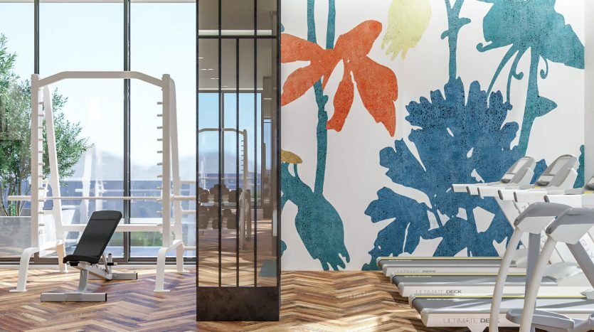 Une salle de sport moderne et bien éclairée ornée de grandes œuvres d'art murales florales, comprenant des appareils de cardio-training et des équipements de musculation. Un ballon d'exercice vert et un tapis de yoga sont posés sur un parquet, avec de grandes fenêtres donnant sur un balcon