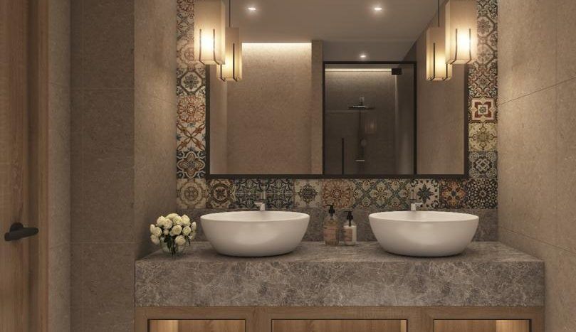 Une salle de bains de villa moderne à Dubaï comprenant deux lavabos blancs sur une vanité en bois avec des étagères de rangement, décorée de carreaux multicolores à motifs au-dessus du miroir et d'un éclairage tamisé.