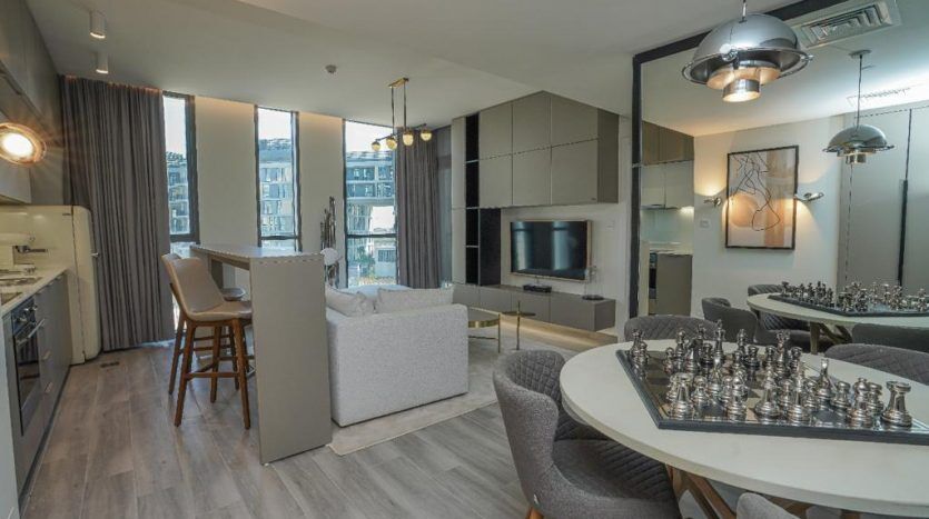 Intérieur d'appartement moderne à Dubaï avec un agencement ouvert avec un salon, une cuisine et un espace salle à manger. La décoration comprend un grand jeu d'échecs sur la table, un mobilier épuré et un éclairage contemporain.