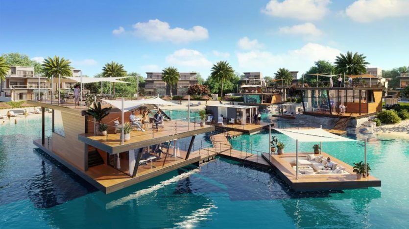 Un complexe luxueux en bord de mer à Dubaï avec une architecture moderne en bois, doté de terrasses, de coins salons extérieurs et de piscines, entouré de paysages luxuriants sous un ciel bleu clair.