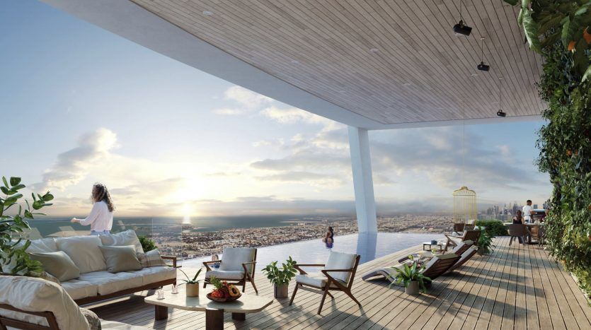 Un toit-terrasse spacieux au coucher du soleil à Dubaï, avec une femme debout près de la balustrade surplombant un paysage urbain, une autre assise et un couple discutant près d'une verdure luxuriante et d'un mobilier d'extérieur élégant.
