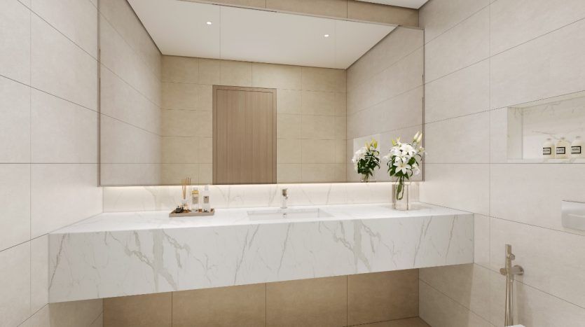Une salle de bains moderne dans une villa à Dubaï comprenant un grand comptoir en marbre avec deux lavabos, des robinets muraux, un grand miroir et des toilettes blanches autoportantes. Des fleurs décoratives sont placées