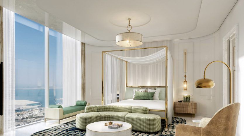 Chambre luxueuse avec un lit à baldaquin blanc, un canapé à rayures vertes et un fauteuil élégant, doté de grandes fenêtres offrant une vue panoramique sur l'océan et une ambiance lumineuse et aérée. Parfait pour ceux qui cherchent à investir