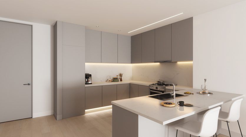 Intérieur de cuisine moderne dans un appartement de Dubaï avec armoires grises, appareils électroménagers intégrés, dosseret en marbre et îlot avec tabourets blancs. Un éclairage lumineux complète la palette de couleurs neutres.