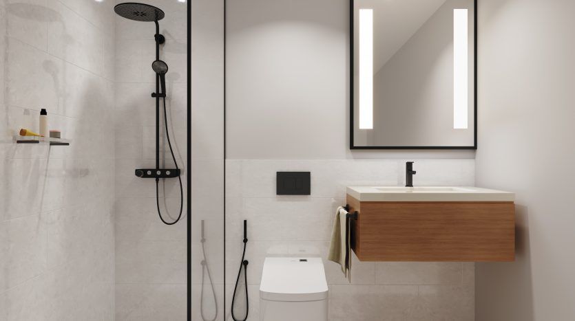 Salle de bains moderne et minimaliste dans une villa de Dubaï avec douche à l'italienne, porte vitrée, lavabo et vasque muraux, toilettes et grand miroir rétroéclairé. L'espace est fini dans des tons neutres