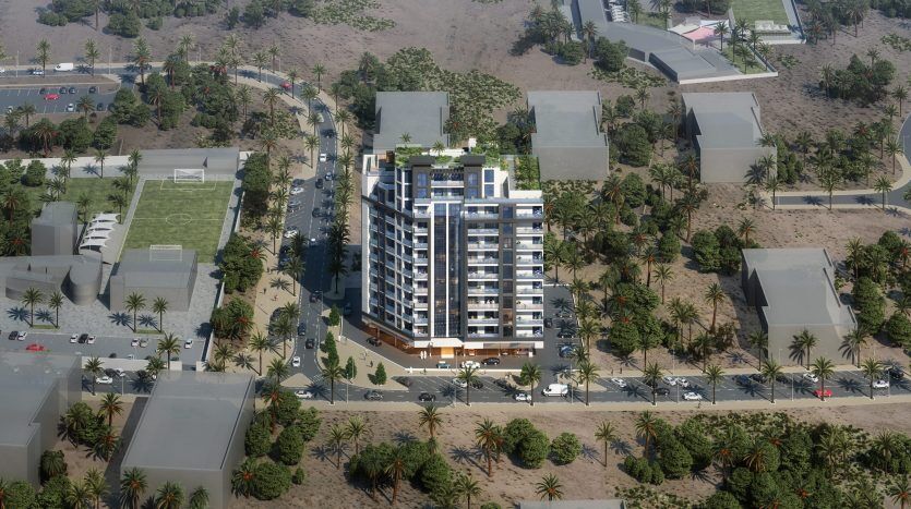 Vue aérienne d'une villa moderne à Dubaï entourée de palmiers luxuriants et de routes paysagées, avec d'autres bâtiments plus petits et des voitures garées visibles dans un cadre suburbain.