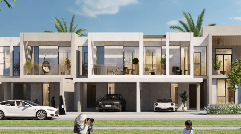 Une rangée contemporaine de maisons de ville à Dubaï par une journée ensoleillée, présentant un design moderne avec balcons et toits plats. Au premier plan, un adulte photographie un enfant jouant avec un ballon de foot sur une pelouse.