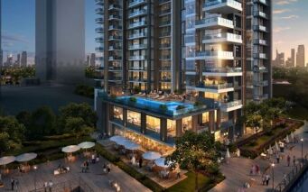 Immeuble d'appartements moderne de grande hauteur doté d'une terrasse spacieuse dotée d'une piscine et de sièges extérieurs, entouré d'une verdure luxuriante au crépuscule, avec les toits de la ville de Dubaï en arrière-plan. Idéal pour ceux qui cherchent à investir