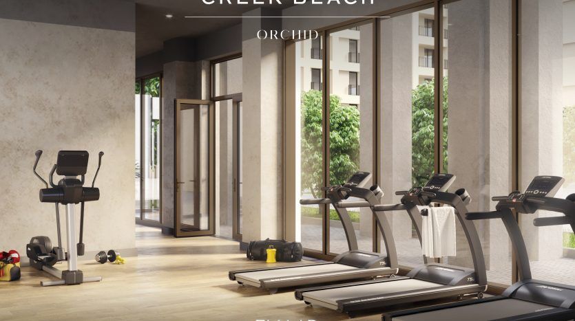 Une salle de sport moderne avec tapis roulants, vélos stationnaires et poids libres donnant sur un espace extérieur serein à travers de grandes fenêtres en verre, présentant un design élégant et minimaliste avec le texte « villa dubai ».