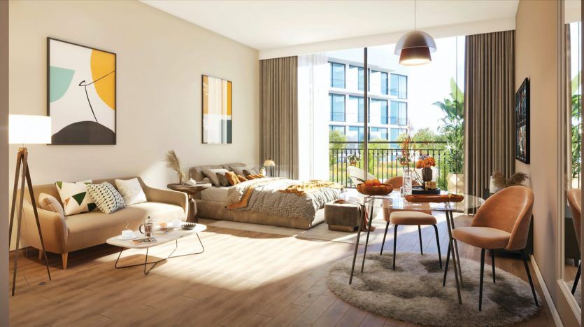 Salon moderne et ensoleillé comprenant un canapé beige, des fauteuils, une table basse et un chevalet d'art. De grandes fenêtres donnent sur un balcon avec des plantes et des œuvres d'art abstraites sont accrochées aux murs