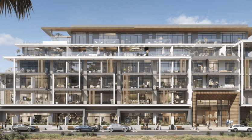 Immeuble moderne de plusieurs étages avec des balcons spacieux, des espaces commerciaux au rez-de-chaussée, des piétons sur le trottoir et des voitures garées le long de la rue, situé dans un environnement urbain ensoleillé à Dubaï.