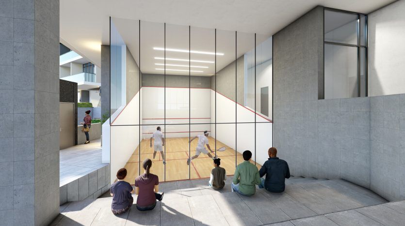 Des gens assis sur un rebord en béton regardent deux joueurs à l'intérieur d'un court de squash couvert avec des murs en verre dans un bâtiment urbain moderne à Dubaï.