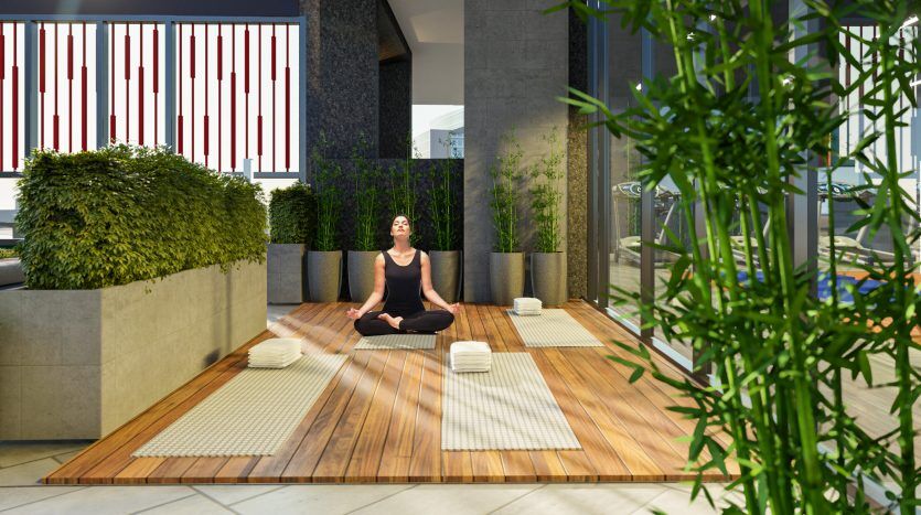Une femme pratiquant le yoga dans un espace intérieur serein d'une villa à Dubaï avec parquet, plantes en pot, paravents décoratifs et éléments architecturaux modernes.