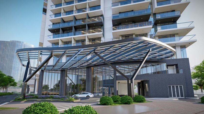 L'entrée d'un immeuble moderne à Dubaï présente un élégant auvent métallique incurvé sur des portes en verre, avec un bâtiment à plusieurs étages avec des balcons en arrière-plan.