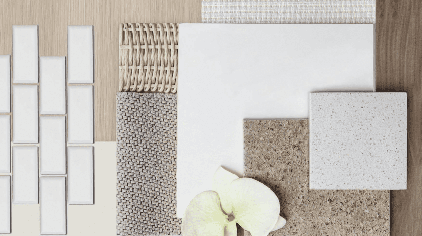 Divers matériaux de décoration intérieure, notamment des carreaux, des tissus et une fleur disposée sur une surface en bois, mettant en valeur différentes textures et couleurs pour la planification de l'aménagement intérieur d'une villa à Dubaï.