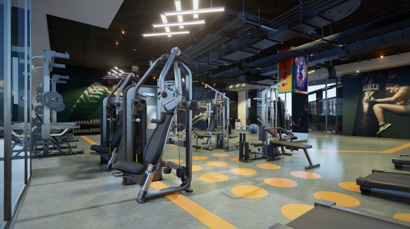 Une salle de sport moderne avec divers appareils d'exercice, éclairée par un éclairage zénithal élégant et de grandes fenêtres sur le côté gauche, présentant un espace de remise en forme intérieur propre et organisé à Dubaï.