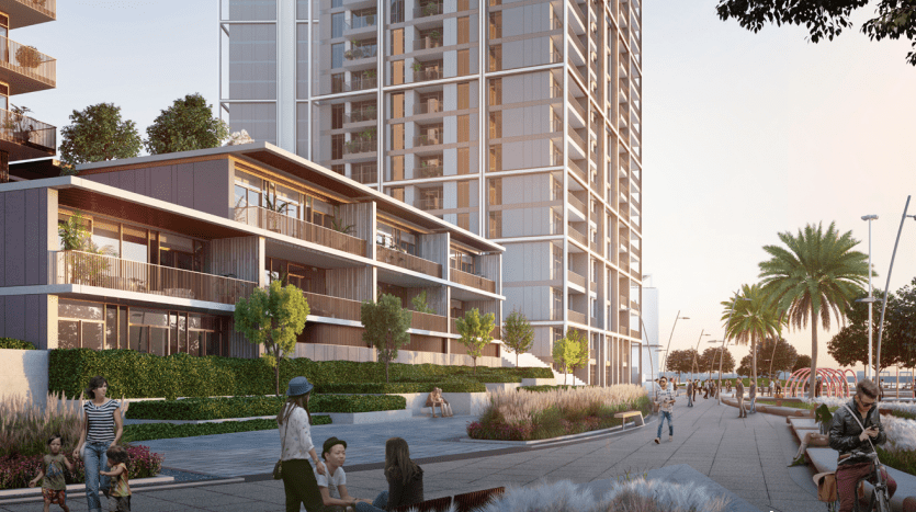 Un rendu architectural d'un développement résidentiel moderne en bord de mer à Dubaï comprenant un immeuble de grande hauteur et des maisons de ville à plusieurs niveaux avec un aménagement paysager luxuriant, des gens marchant et profitant de l'espace extérieur sous un ciel coucher de soleil.
