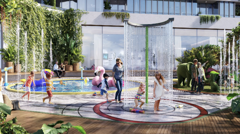 Luxueux jardin sur le toit de Dubaï, avec des familles et des enfants jouant dans une pataugeoire circulaire avec des fontaines d'eau suspendues, entouré d'une verdure luxuriante, de coins salons et d'un horizon de la ville en arrière-plan.