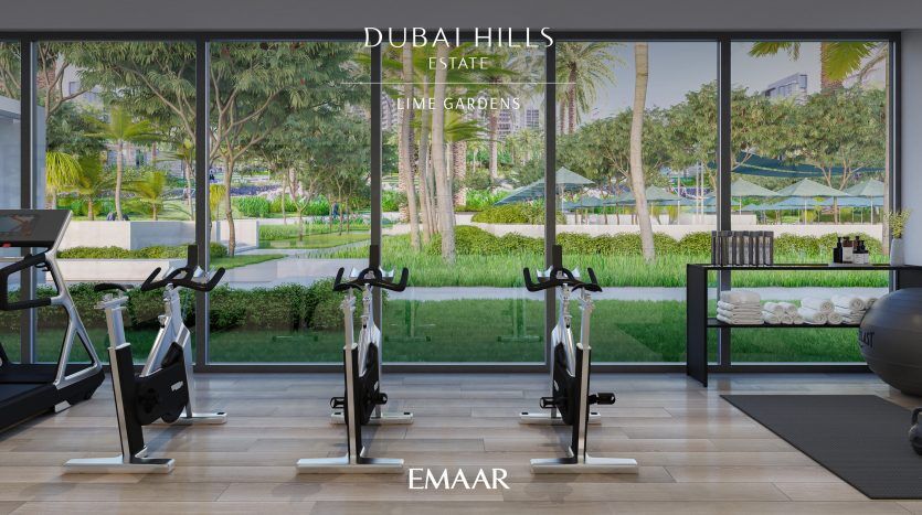 Une salle de sport moderne avec de grands murs de verre donnant sur des jardins luxuriants dans la villa Dubai Hills. Il contient des tapis roulants, des vélos stationnaires et des serviettes soigneusement empilées.