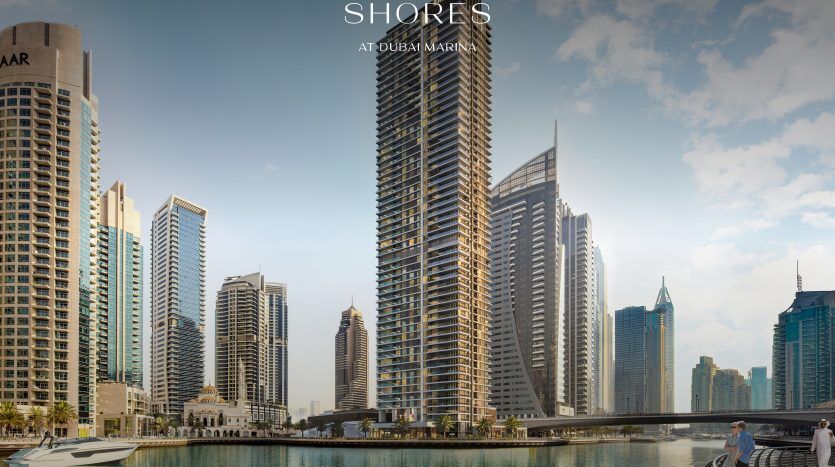 Une vue panoramique de la marina de Dubaï, avec des immeubles modernes au bord de l'eau, avec un ciel dégagé et une personne marchant sur un pont au premier plan. Le texte « Marina Shores à