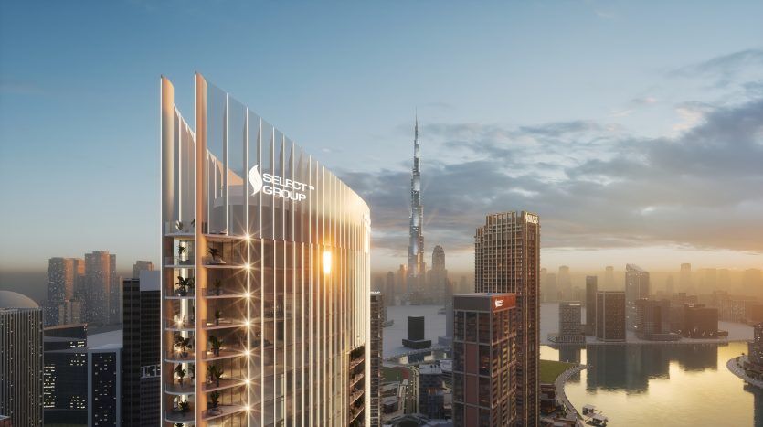 Une vue panoramique sur les toits d'une ville moderne au coucher du soleil, avec un bâtiment important avec le logo « Select Group » et une haute tour en arrière-plan, à Dubaï.