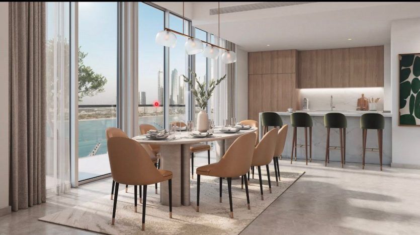 Dining area and modern kitchen with a large window overlooking a coastal view. The dining table seats six, and there are green stools at the kitchen bar in the Dubai villa.