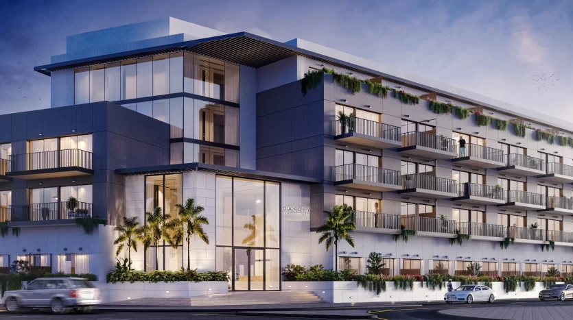 Immeuble d'appartements moderne à Dubaï au design élégant avec de grands balcons et balustrades en verre, entouré d'une verdure luxuriante, éclairé au crépuscule.