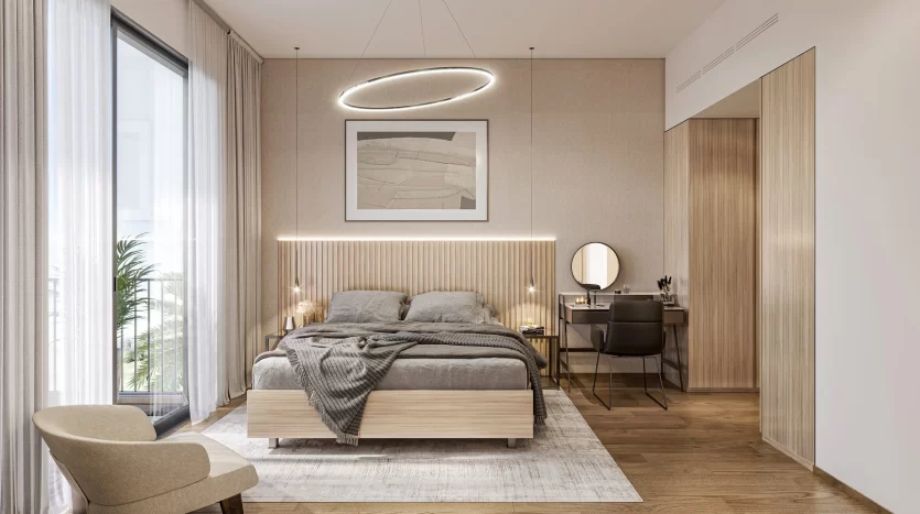 Une chambre moderne dans une villa de Dubaï avec des touches de bois et des tons neutres. Elle comprend un grand lit avec une literie grise, un miroir rond sur un bureau, une chaise et un éclairage d'ambiance, dont un