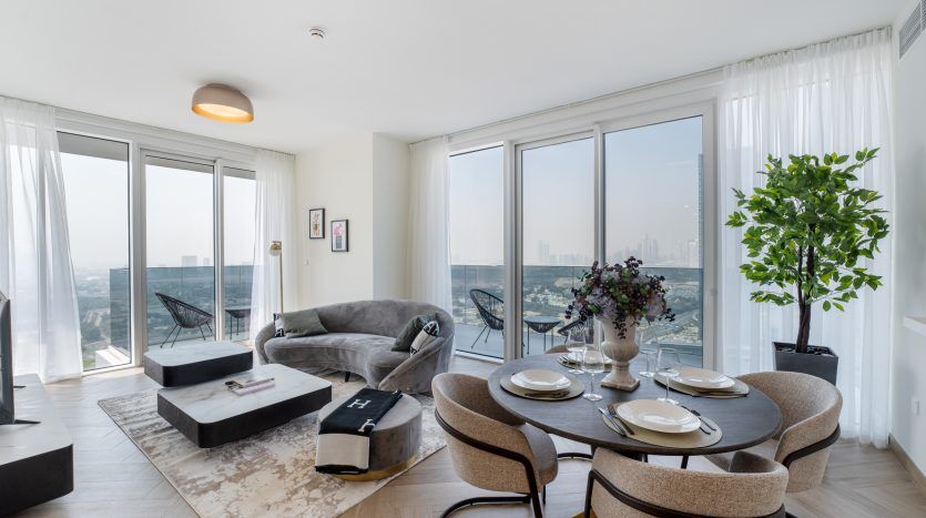 Salon moderne dans une villa de Dubaï, doté de grandes fenêtres avec vue sur les toits de la ville, d'un mobilier élégant et d'une plante en pot, créant un espace lumineux et aéré.